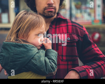 Ein kleines Kind wird in einer Schlinge im Freien, der von seinem Vater durchgeführt Stockfoto