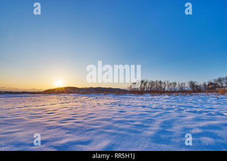 Schönen Sonnenuntergang szenischen der Stadt in der Nähe von Toyokoro Tokachi River im Winter im Südosten der Stadt Obihiro, Hokkaido, Japan. Stockfoto