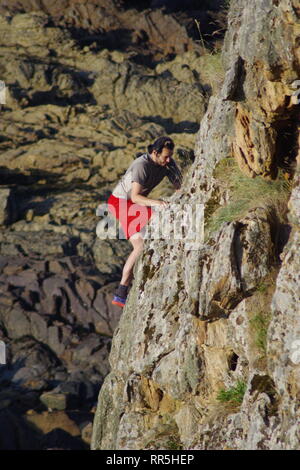 Kletterer, junger Mann Free Climbing Maidens Rock, Sandstein Sea Stack in der Nähe von St. Andrew's, auf einem Fine Summers Night. Fife, Schottland, Großbritannien. Stockfoto