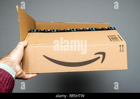 Paris, Frankreich, 23.Februar 2019: Mann, gegen den grauen Hintergrund Amazon Prime Karton mit Smile Amazon Pfeil Schriftzug geöffnet Stockfoto