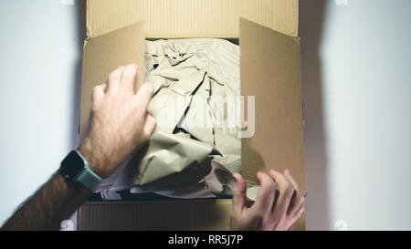 Blick von oben der Mann die Hände Auspacken der neuen Karton vor weißem Hintergrund - Ecommerce im Büro zu Hause geliefert Stockfoto