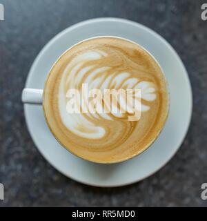 Kaffee Kunst in weiße Tasse mit Untertasse auf dem grauen Stein Oberfläche des Tisches. Stockfoto