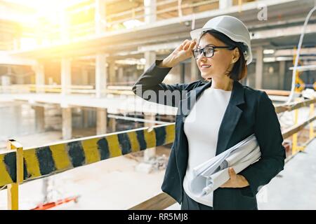 Portrait von erwachsenen weiblichen Baumeister, Ingenieur, Architekt, Inspector, Manager bei der Baustelle. Frau mit Plan, auf Gebäude. Stockfoto