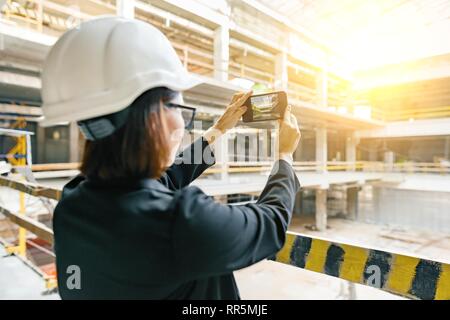 Portrait von erwachsenen weiblichen Baumeister, Ingenieur, Architekt, Inspector, Manager bei der Baustelle. Frau macht Foto des Gebäudes. Stockfoto