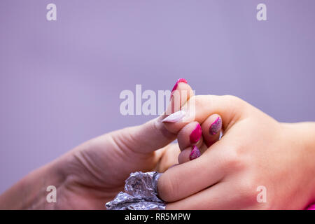 Women's Hand mit Alufolie auf Nägel Nagelstudio. Stockfoto