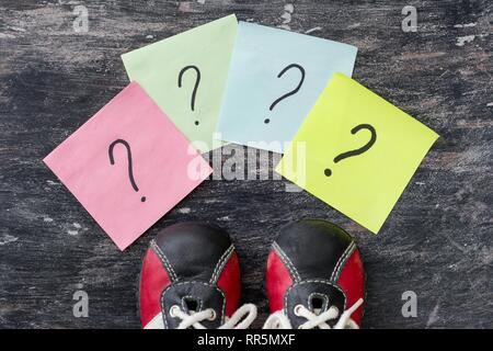 Viele Fragezeichen vor Sneakers. Schwarzer Hintergrund Stockfoto