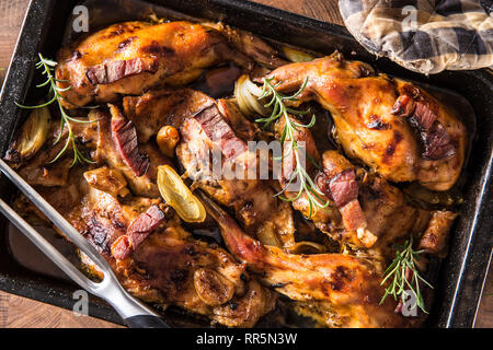 Oben auf Ansicht gebratenes Kaninchen mit Zwiebel Knoblauch Speck und Kräutern. Stockfoto