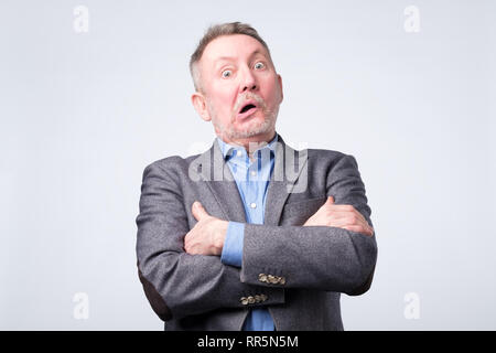 Älterer Mann im Anzug ist verwundert und verwirrt Nachsinnen über geschäftliche Probleme. Stockfoto