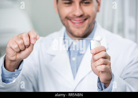 Selektiver Fokus der Zahnseide in die Hände der freundlichen Zahnarzt Stockfoto