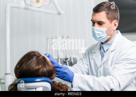 Schwere Zahnarzt in Latex Handschuhe und Masken arbeiten mit weiblichen Patienten Stockfoto