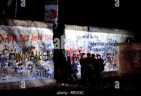 Ost und West deutschen Wachen converse an die neu geschaffene Öffnung der Berliner Mauer nach einem Kran ein Abschnitt der Struktur neben dem Brandenburger Tor entfernt. Stockfoto