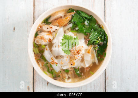 Asiatische Kway Teow Suppe, Nudeln und Huhn in Schüssel auf Holz- Hintergrund. Ansicht von oben flach. Stockfoto