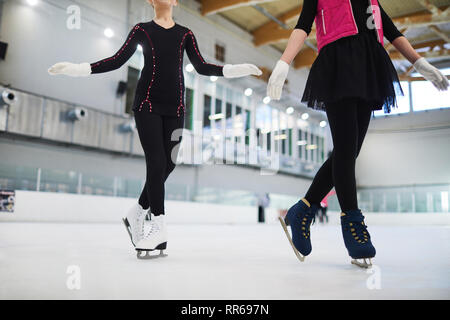 Niedrige Abschnitt Porträt von zwei unkenntlich Eiskunstläufer auf der Eisbahn in niedlichen Outfits Posing, kopieren Raum Stockfoto