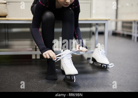 Niedrige Abschnitt Portrait von unkenntlich Mädchen binden skating Schuh im Ankleidezimmer, bevor die Praxis, kopieren Raum Stockfoto