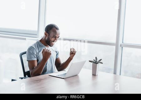 Professionelle männlichen Ökonom sucht benötigten Informationen auf tragbaren Computer, happy High Net Profit zu erhalten, verbringt wichtige Bank- betrieb. Ha Stockfoto