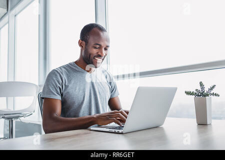 Professionelle männlichen Ökonom sucht benötigten Informationen auf tragbaren Computer, happy High Net Profit zu erhalten, verbringt wichtige Bank- betrieb. Af Stockfoto