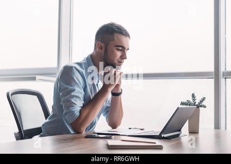 Professionelle männlichen Ökonom sucht benötigten Informationen auf tragbaren Computer, happy High Net Profit zu erhalten, verbringt wichtige Bank- betrieb. Yo Stockfoto