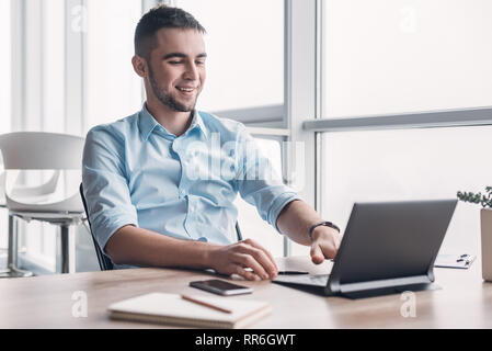 Professionelle männlichen Ökonom sucht benötigten Informationen auf tragbaren Computer, happy High Net Profit zu erhalten, verbringt wichtige Bank- betrieb. Yo Stockfoto