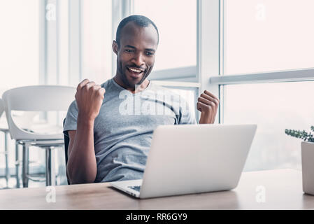 Professionelle männlichen Ökonom sucht benötigten Informationen auf tragbaren Computer, happy High Net Profit zu erhalten, verbringt wichtige Bank- betrieb. Ha Stockfoto