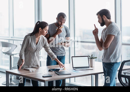 Gruppe von attraktiven multirassischen Geschäftsleute gemeinsam kreative Büro beim Stehen in der Nähe des Schreibtisch aus Holz , multi-ethnischen Business Team Diskussion von Fragen in der Sitzung Stockfoto