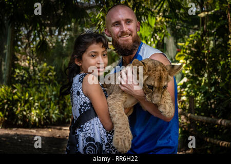 Kaukasische Mann und Latin girl Holding baby Löwe in der Guatemaltekischen zoo Stockfoto