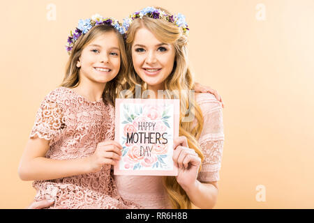 Lächelnde Mutter und Tochter in floralen Kränze glücklich Muttertag holding Grußkarte auf gelbem Hintergrund Stockfoto