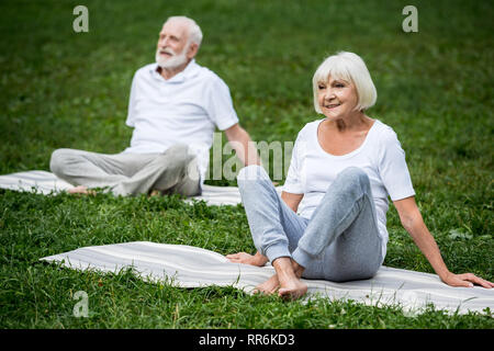 Senior paar Meditation in Entspannung stellt sich beim Sitzen auf Yoga Matten Stockfoto