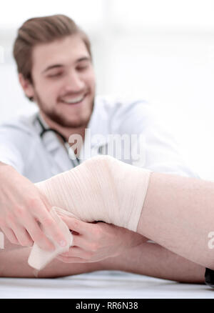 Arzt bandagieren eine Wunde am Bein des Patienten Stockfoto