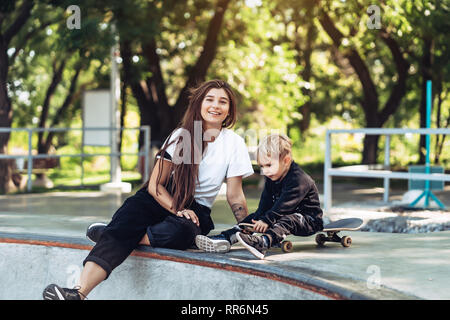 Schöne junge Hipster Mamma und kleinen Sohn Am Skatepark Stockfoto