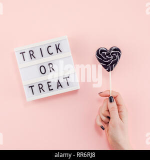 Kreative Halloween Tag Zusammensetzung flach Top View Holiday Feier mit süßen schwarzen lollipop Herz hand Lightbox rosa Papier Hintergrund Kopie spac Stockfoto