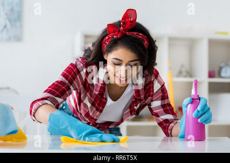 Ziemlich afrikanische amerikanische Frau Reinigung Tabelle mit gelben Lappen Stockfoto