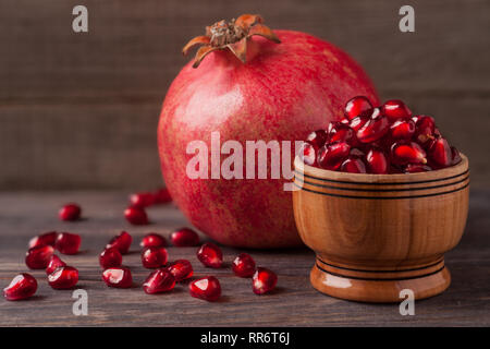 Ein Granatapfel und Körner in die Schüssel auf den alten hölzernen Hintergrund Stockfoto