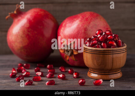 Zwei Granatapfel und Körner in die Schüssel auf den alten hölzernen Hintergrund Stockfoto