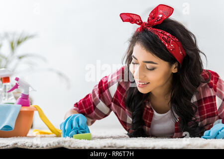 Ziemlich afrikanische amerikanische Frau im Plaid Shirt Reinigung Teppich Stockfoto