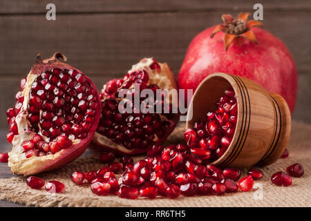 Granatapfel und Körner in die Schüssel auf den alten hölzernen Brett mit Sack Stockfoto