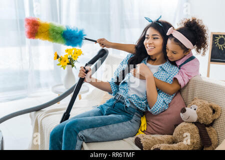 Cute afrikanische amerikanische Kind umarmen Mutter aus zurück halten bunte Duster Stockfoto
