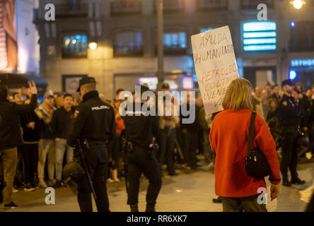 Madrid, Spanien. 24 Feb, 2019. Auseinandersetzungen zwischen den Anhängern des Maduro und der Opposition fand in Madrid statt. Der Ursprung des Streits war eine Demonstration, die von den Verfechtern der Maduro an der Puerta del Sol organisiert gegen die Intervention von Spanien in Venezuela zu protestieren. Bürger Venezuelas von der Opposition bis gezeigt und der Intervention der Polizei war notwendig Keine stärkere Auseinandersetzungen zwischen beiden Teilen zu vermeiden. Im Bild, auf der einen Seite eine Frau die Unterstützung Maduro mit einem Plakat mit der Aufschrift "Humanitäre Hilfe = Öl" und auf der anderen Seite der Polizei Barriere der Opposition von Maduro ist Stockfoto