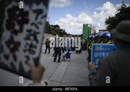 NAGO, Japan - 25. Februar: Demonstranten mit Plakaten stehen vor dem Tor, während Baufahrzeuge betritt den Ort während der Protest gegen US-Basis außerhalb der USA Basislager Schwab Tor, die am 25. Februar 2019 in Nago, Präfektur Okinawa, Japan. Auf der Grundlage der Präfektur Referendums, mehr als 70 Prozent der Wähler in Okinawa lehnen US-base in Henoko. (Foto von Richard Atrero de Guzman/LBA) Stockfoto