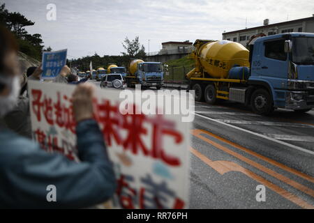 NAGO, Japan - 25. Februar: Demonstranten mit Plakaten stehen vor dem Tor, während Baufahrzeuge betritt den Ort während der Protest gegen US-Basis außerhalb der USA Basislager Schwab Tor, die am 25. Februar 2019 in Nago, Präfektur Okinawa, Japan. Auf der Grundlage der Präfektur Referendums, mehr als 70 Prozent der Wähler in Okinawa lehnen US-base in Henoko. (Foto von Richard Atrero de Guzman/LBA) Stockfoto