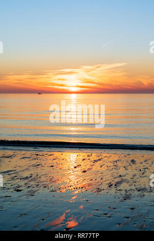 Sonnenaufgang, Sonnenaufgang über dem Meer, Ärmelkanal, bei Viking Bay Broadstairs. Dünne Band von Cloud und orange Himmel am Horizont mit klaren, blauen Himmel darüber. Einzelne boot Silhouette am Meer. Küste im unteren Rahmen. Stockfoto