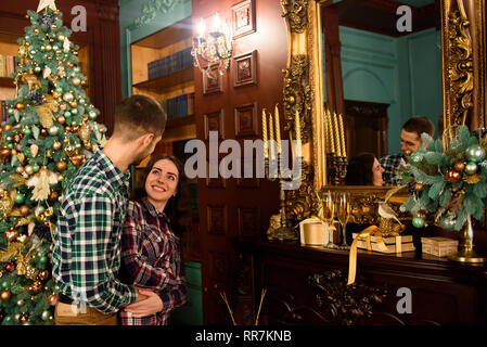 Ein Kerl mit einem Mädchen Weihnachten feiert. Ein liebevolles Paar genießt jede andere am Silvesterabend in einer familiären Umgebung. Stockfoto