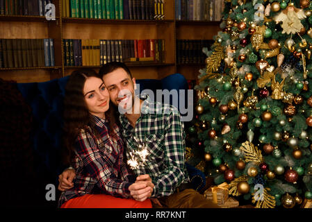 Junge schöne Küsser und brennenden Wunderkerzen. Liebende Paar in Weihnachten eingerichtete Zimmer. Stockfoto