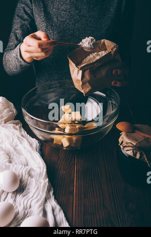 Nahaufnahme der weiblichen Hand Tasche und gehäuften Löffel Mehl in Schüssel mit gewürfelte Butter Teig gießen für Kreis zu machen. Frau kochen Hausgemachte cak Stockfoto