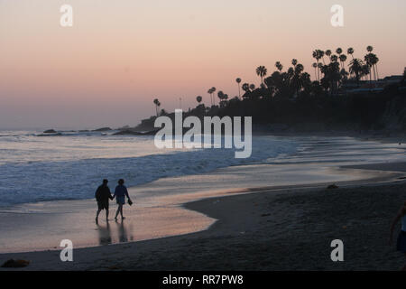 Eine Silhouette von ein paar Hand in Hand auf der Küstenlinie von Laguna Beach, Kalifornien. Stockfoto