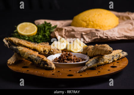 In der Pfanne gebratener Fisch mit Polenta, Pecan und Knoblauch Sauce Stockfoto