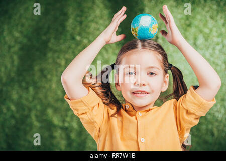 Adorable kid Holding globe Modell auf Kopf auf unscharfen Hintergrund, Tag der Erde Konzept Stockfoto