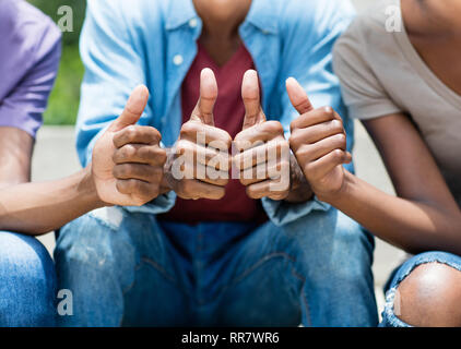 Afrikanische amerikanische junge Erwachsene mit Daumen hoch, im Sommer im Freien Stockfoto