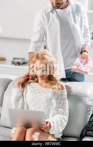 Teilansicht der Mann im weißen T-Shirt, Geschenk für Mädchen mit Laptop Stockfoto