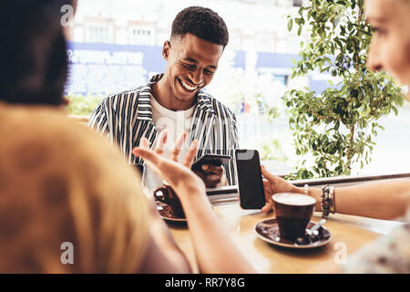 Gruppe von kreativen Menschen treffen sich im Cafe. Lächelnden jungen Freunde. Im Café mit Smart Phones sitzen. Stockfoto