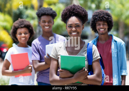 Afrikanische Studentin mit der Gruppe der afrikanischen amerikanischen Studenten Outdoor im Sommer Stockfoto